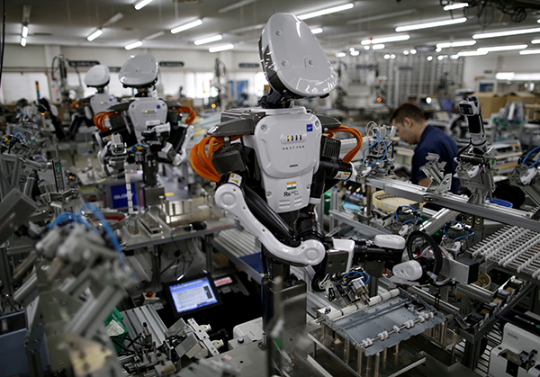 FILE PHOTO: Humanoid robots work side by side with employees in the assembly line at a factory of Glory Ltd., a manufacturer of automatic change dispensers, in Kazo, north of Tokyo